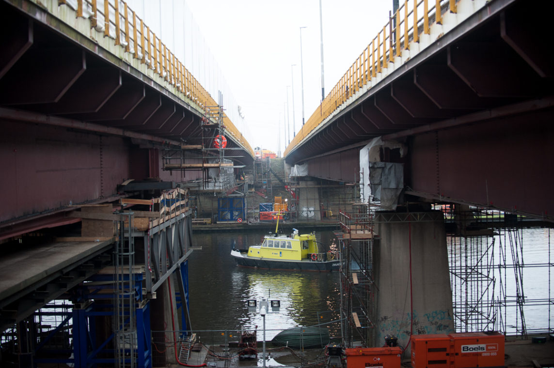 Werkzaamheden aan een brug, een boot van Rijkswaterstaat vaart langs