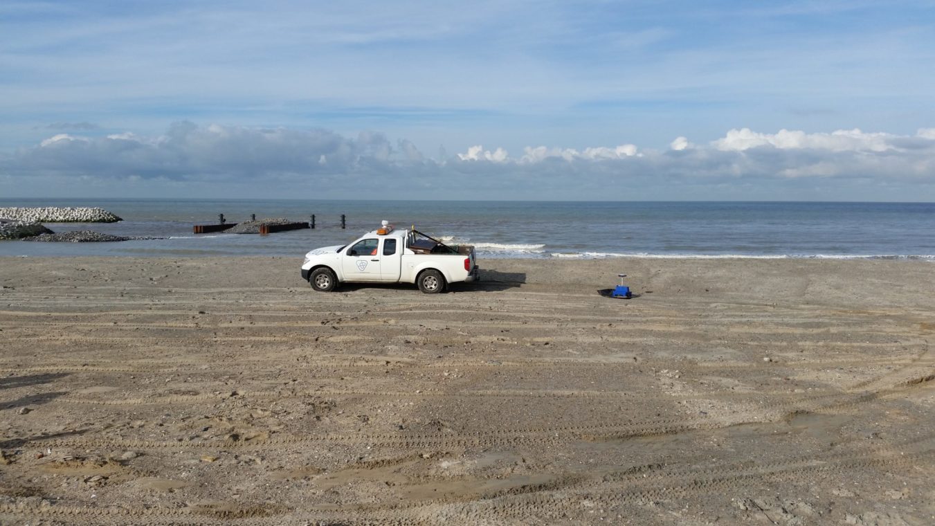 Een auto van Waterschap Scheldestromen rijdt over het strand