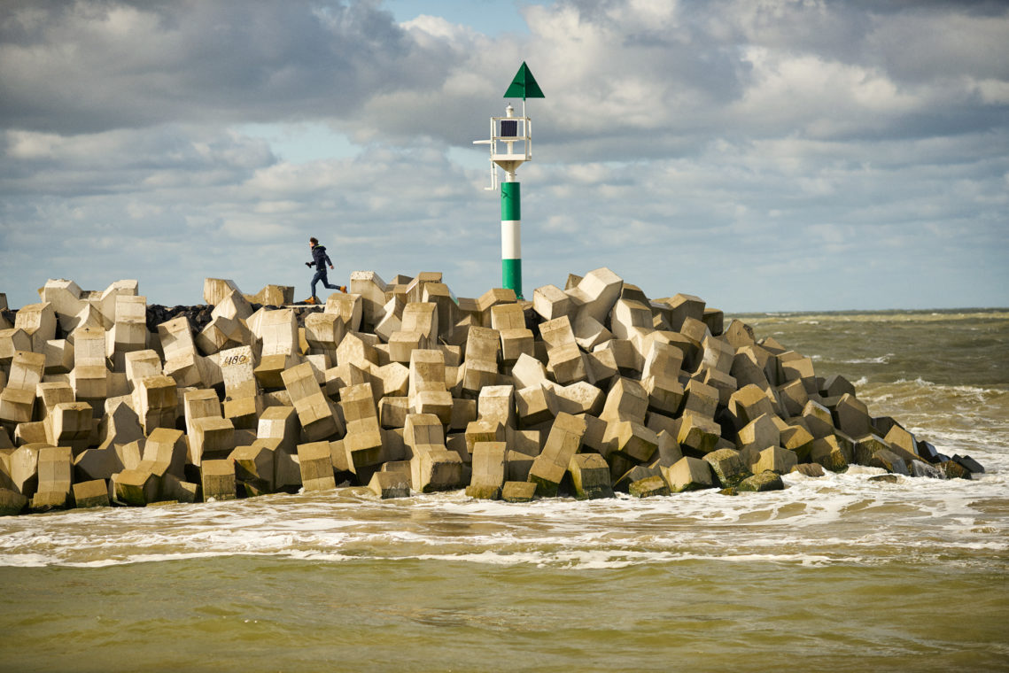 Iemand loopt op een strekdam bij de Haven van Cadzand-Bad