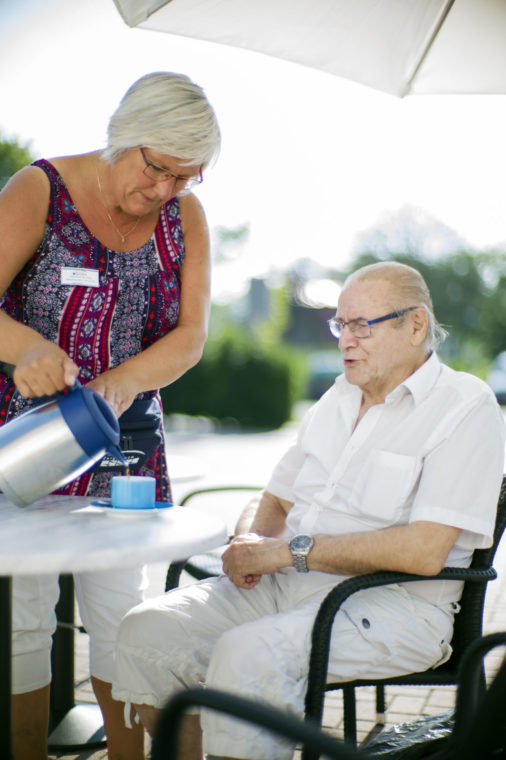 Een dame schenkt koffie in voor een oudere meneer