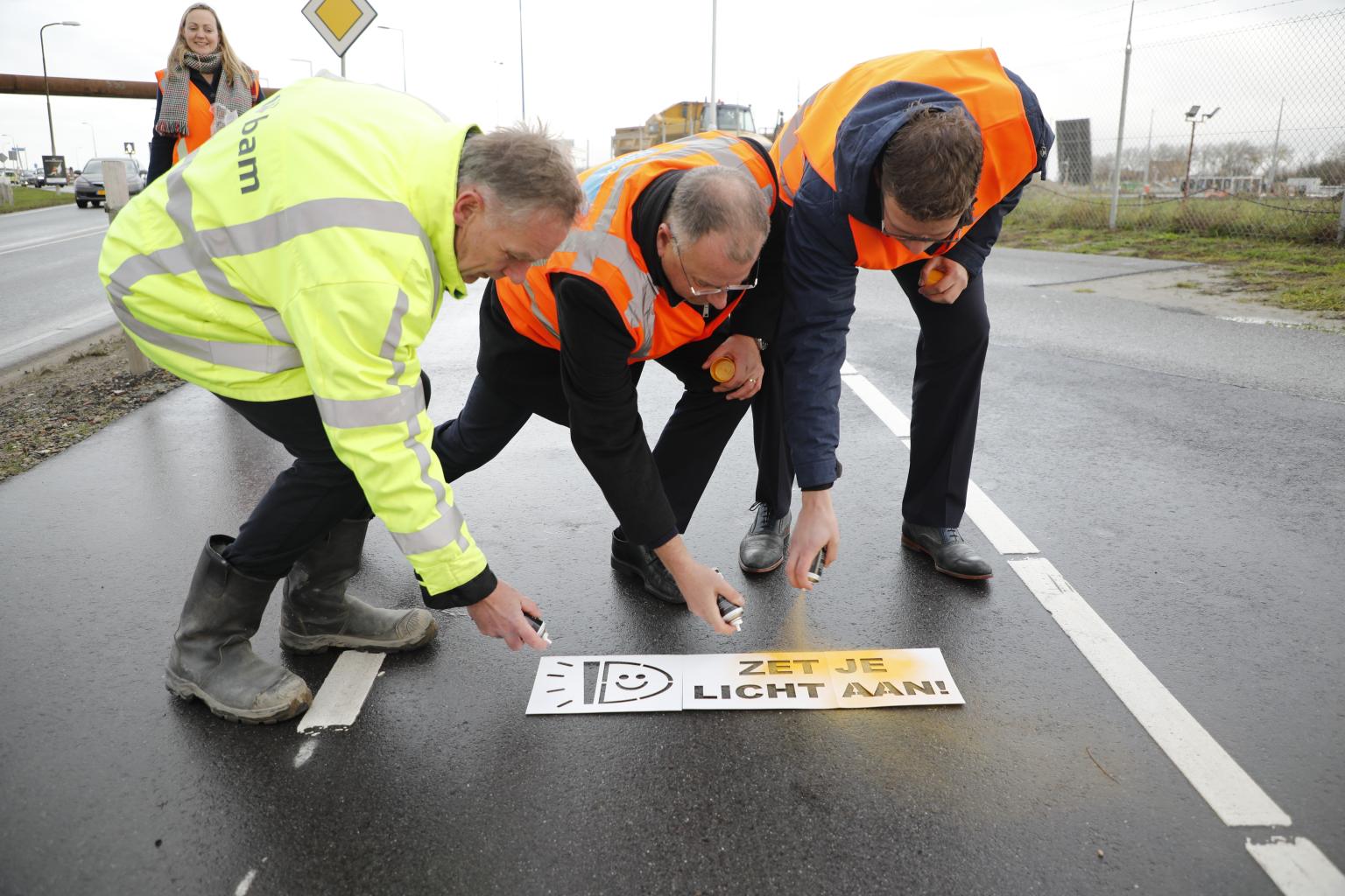 Werknemers spuiten 'Zet je licht aan!' op een fietspad bij de Nieuwe Sluis Terneuzen