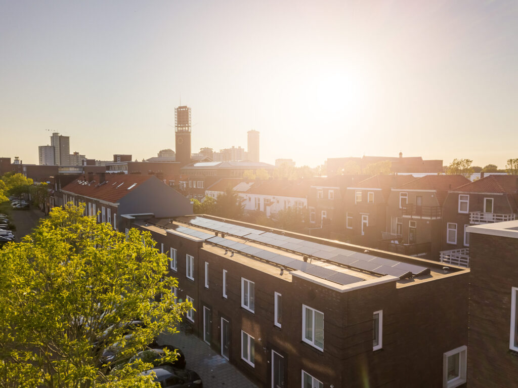 Foto van een nieuw rijtje huizen met zonnepanelen in Vlissingen met een ondergaande zon op de achtergrond