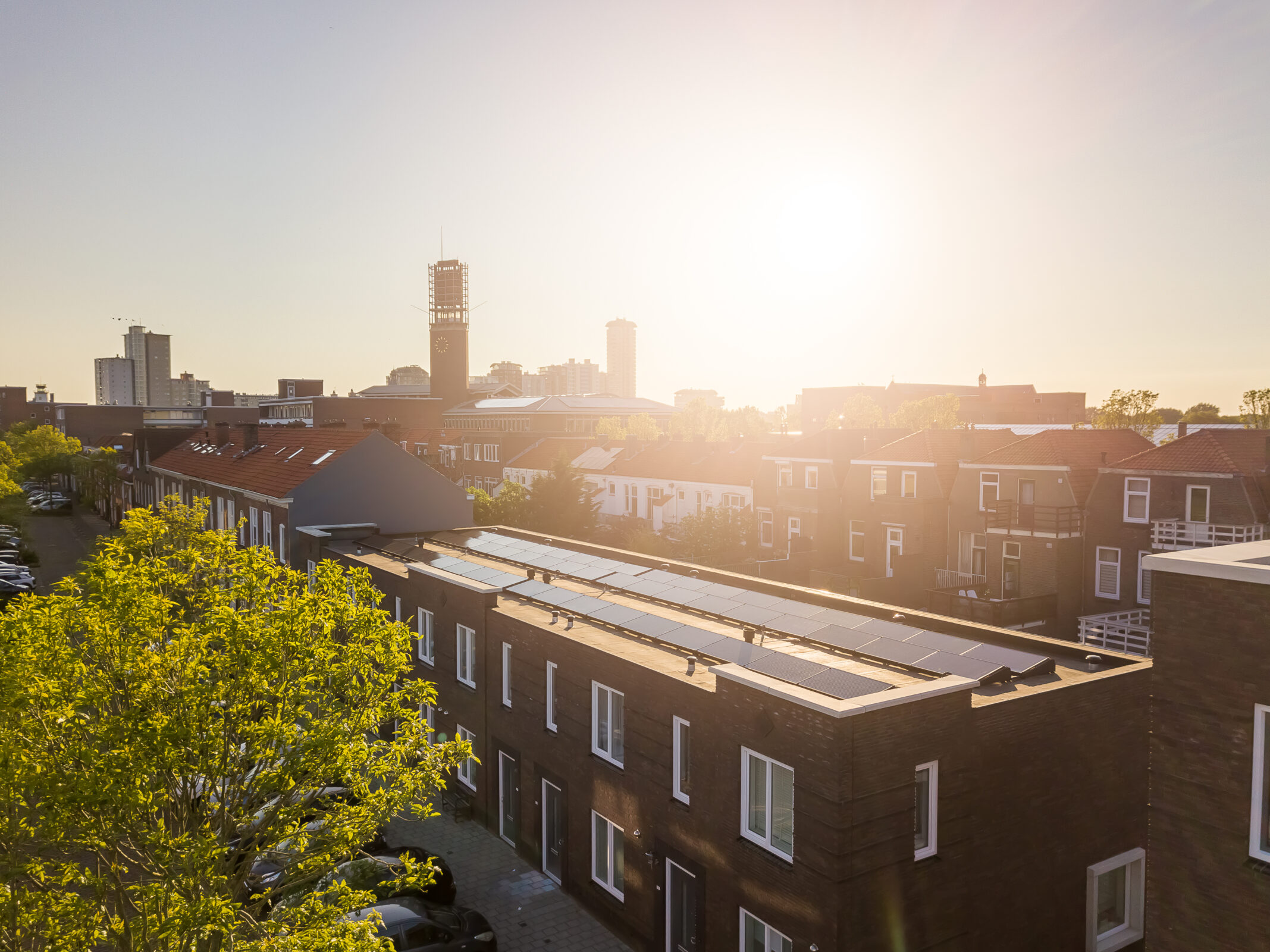 Foto van een nieuw rijtje huizen met zonnepanelen in Vlissingen met een ondergaande zon op de achtergrond