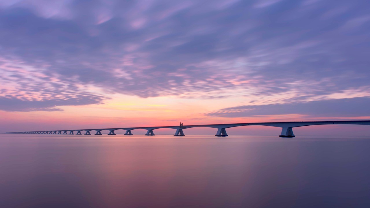 De Zeelandbrug met een gekleurde lucht van de ondergaande zon.