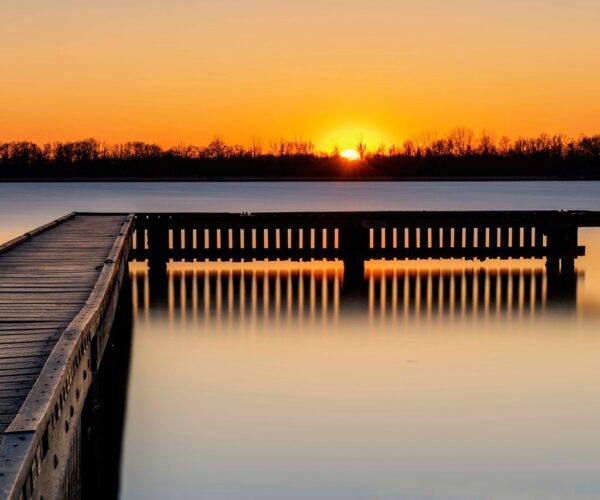 Een stijger op het water met ondergaande zon op de achtergrond.