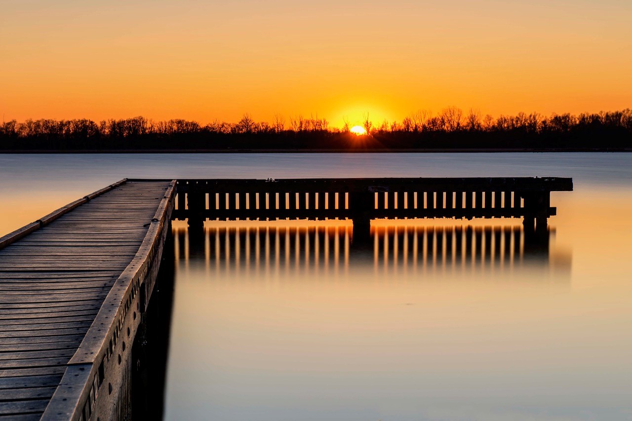 Een stijger op het water met ondergaande zon op de achtergrond.