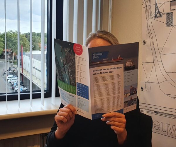 Een vrouw leest de brochure van de Nieuwe Sluis Terneuzen.