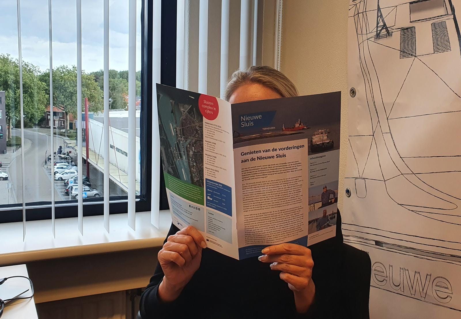 Een vrouw leest de brochure van de Nieuwe Sluis Terneuzen.
