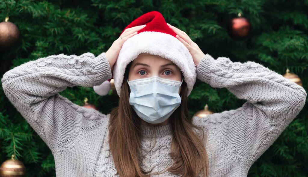 Een vrouw met een mondkapje en een kerstmuts op.