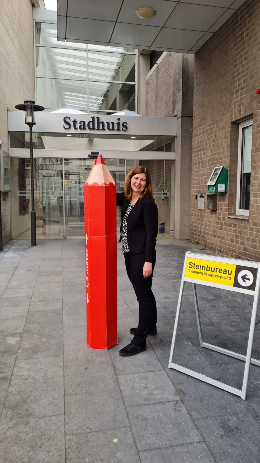 Anneloes met een grote versie van het rode stempotlood voor het stadhuis in Hulst