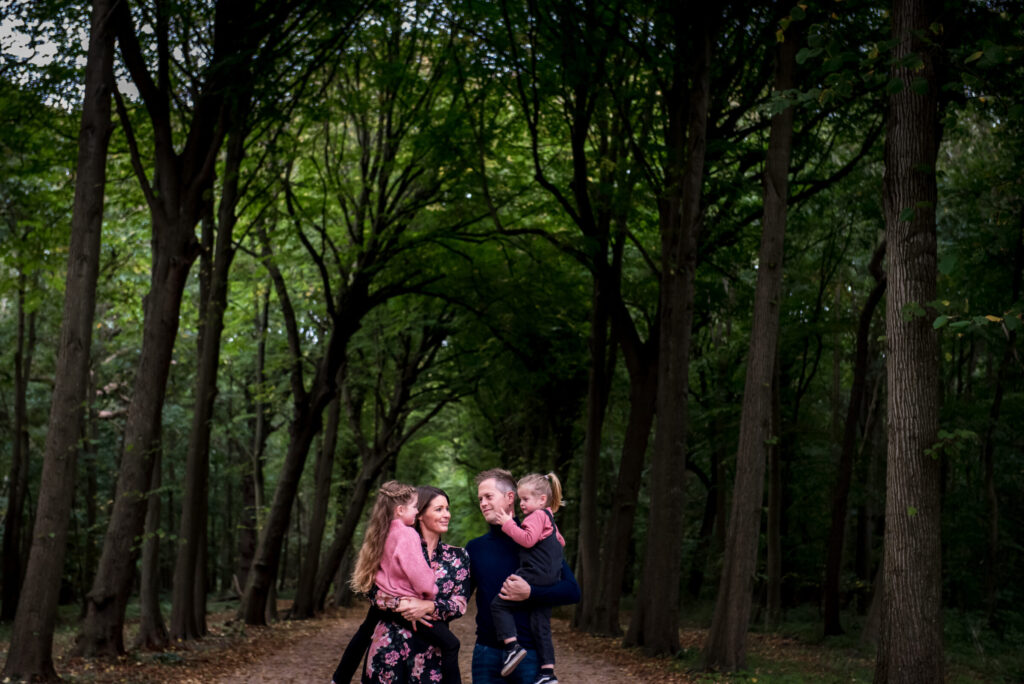 Gezin met man en vrouw en twee kinderen in het bos in Zeeland.