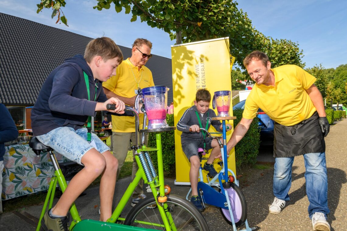 Kinderen trappen hard op een fiets om elektriciteit op te wekken zodat ze een smoothie kunnen maken