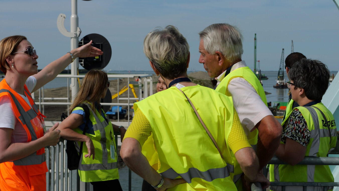 Mensen in gele hesjes luisteren naar een gids die uitleg geeft