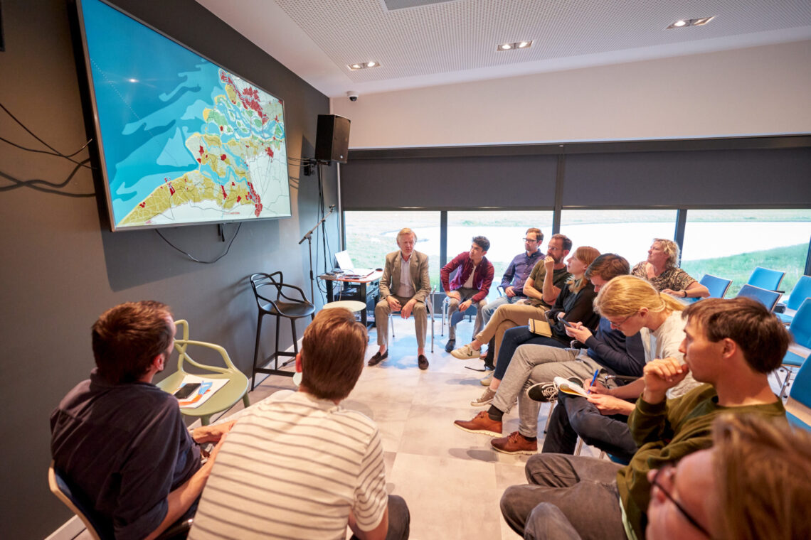 Mensen in de zaal kijken aandachtig naar een presentatie over de toekomst van de Zuidwestelijke Delta