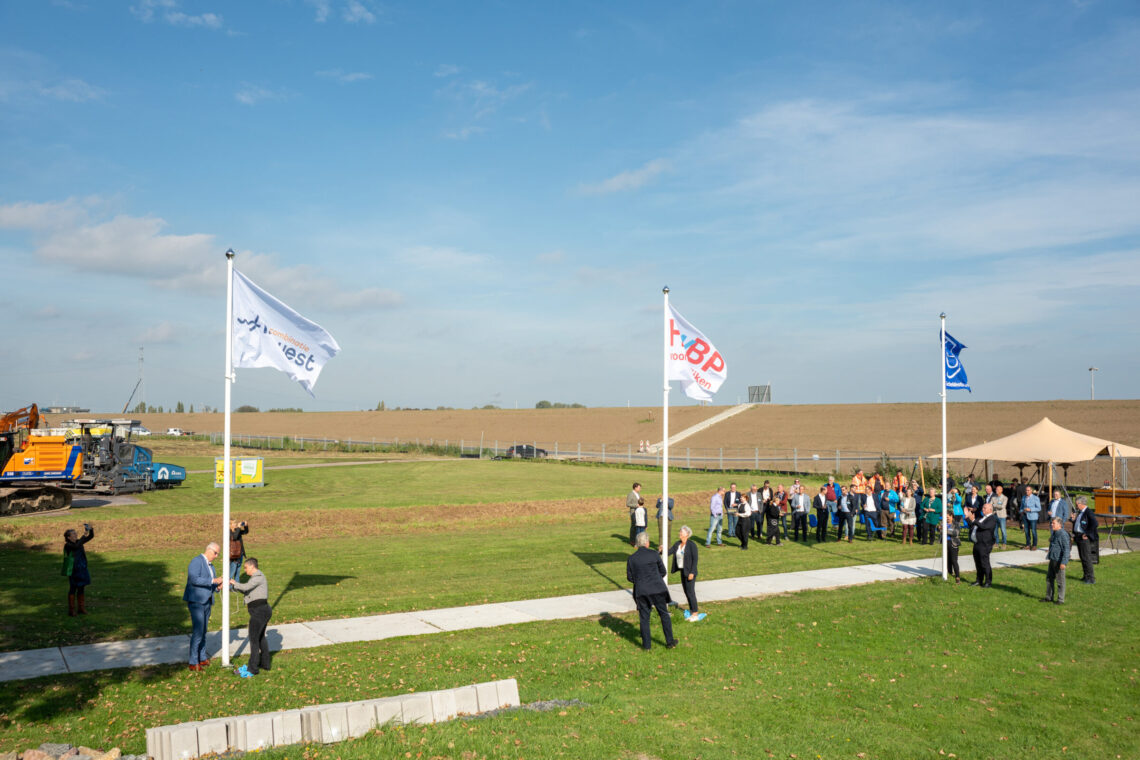 Mensen hijsen drie vlaggen bij het infocentrum Dijkversterking Hansweert